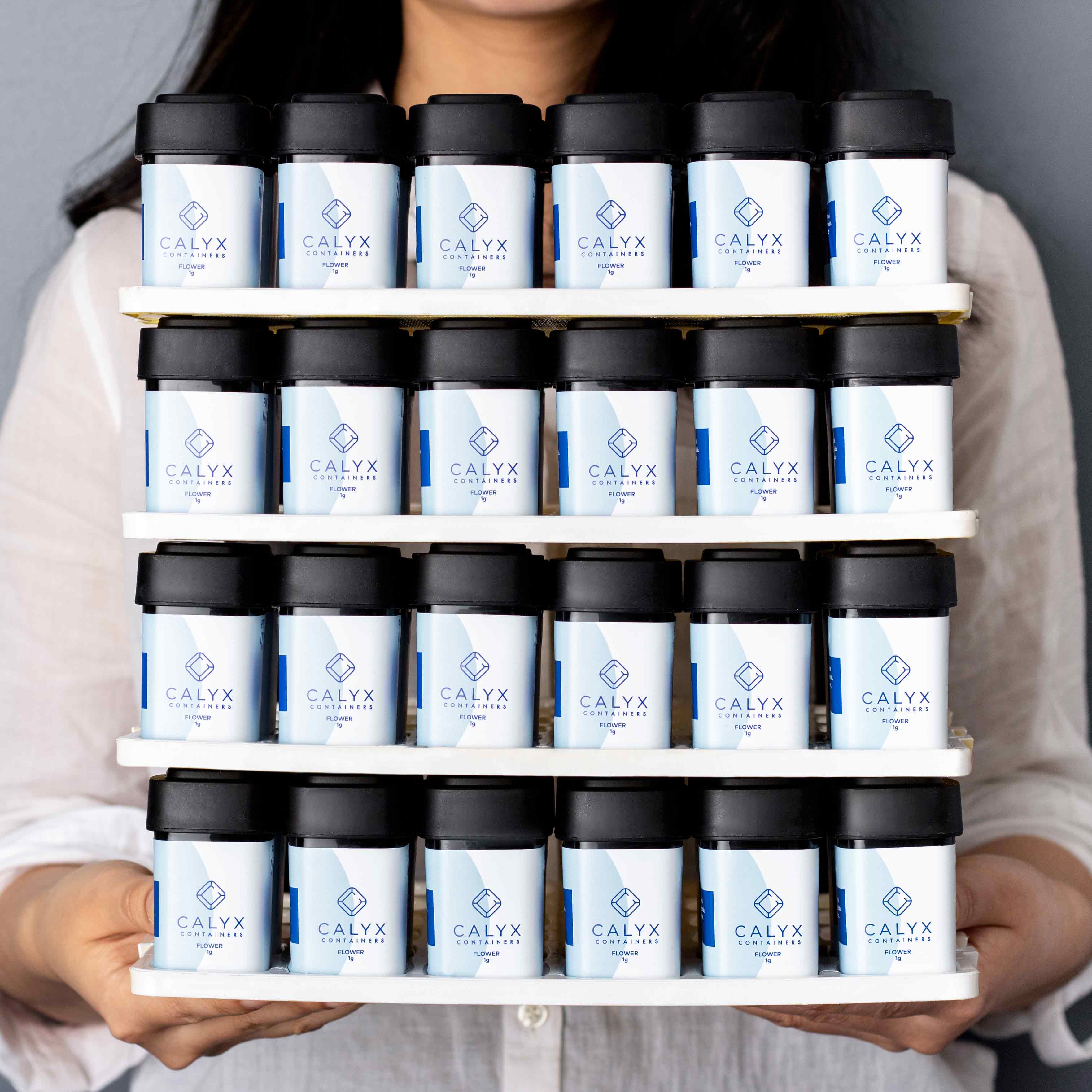 Woman holding four insert trays filled with Calyx drams with custom Calyx branding