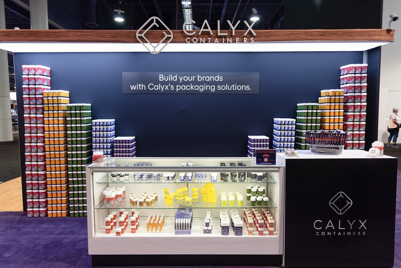 Calyx Containers show booth at MJBiz with stacks of organized Calyx products