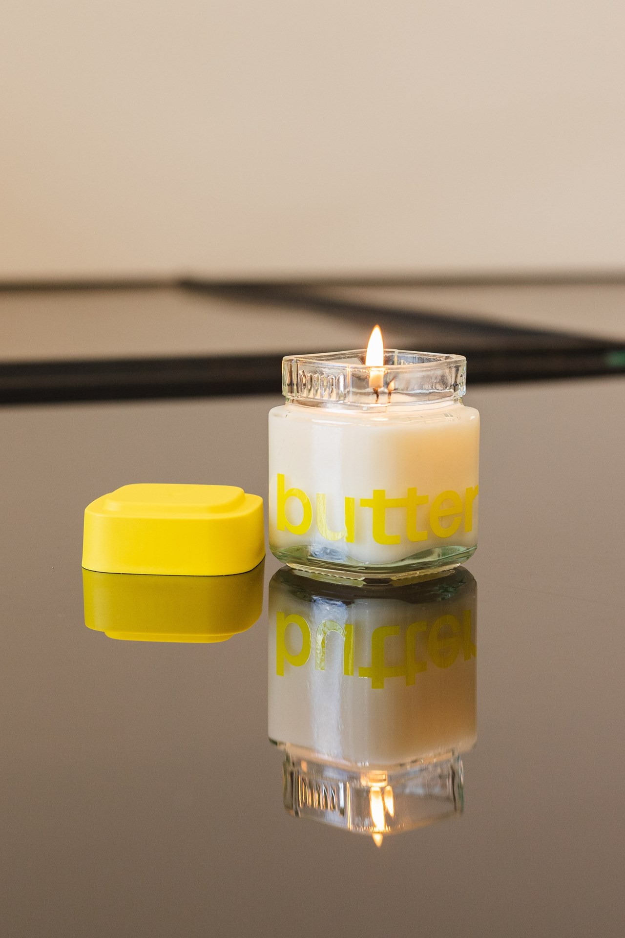 Calyx jar with Butter logo being reused as a candle holder filled with wax and lit wick