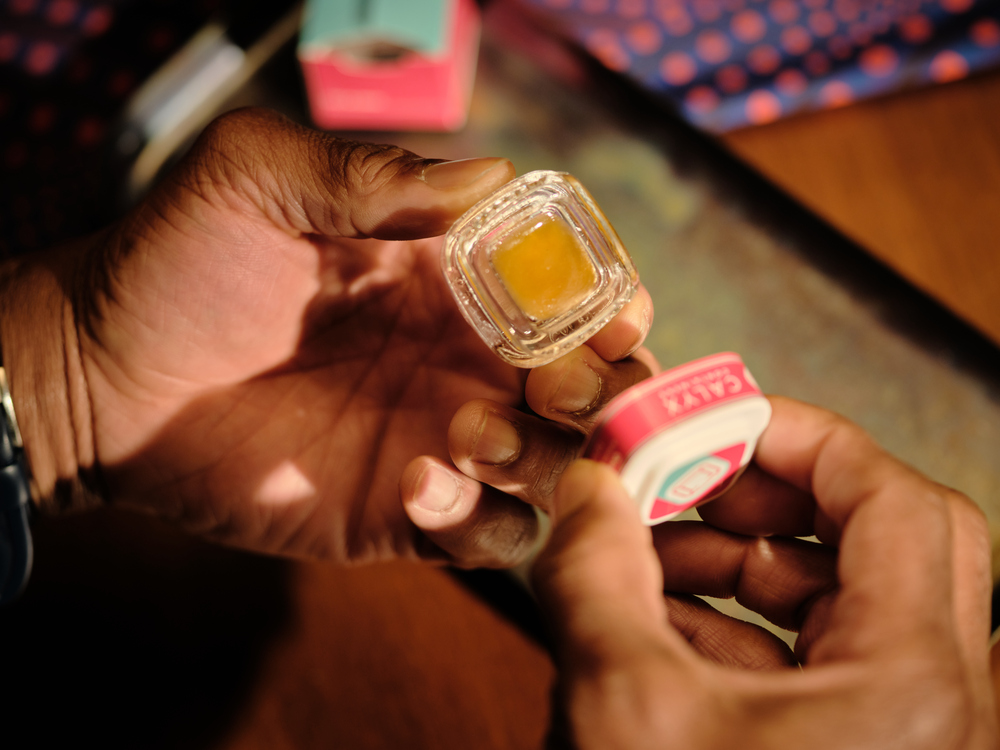 Person holding a Calyx concentrate container filled with cannabis concentrate