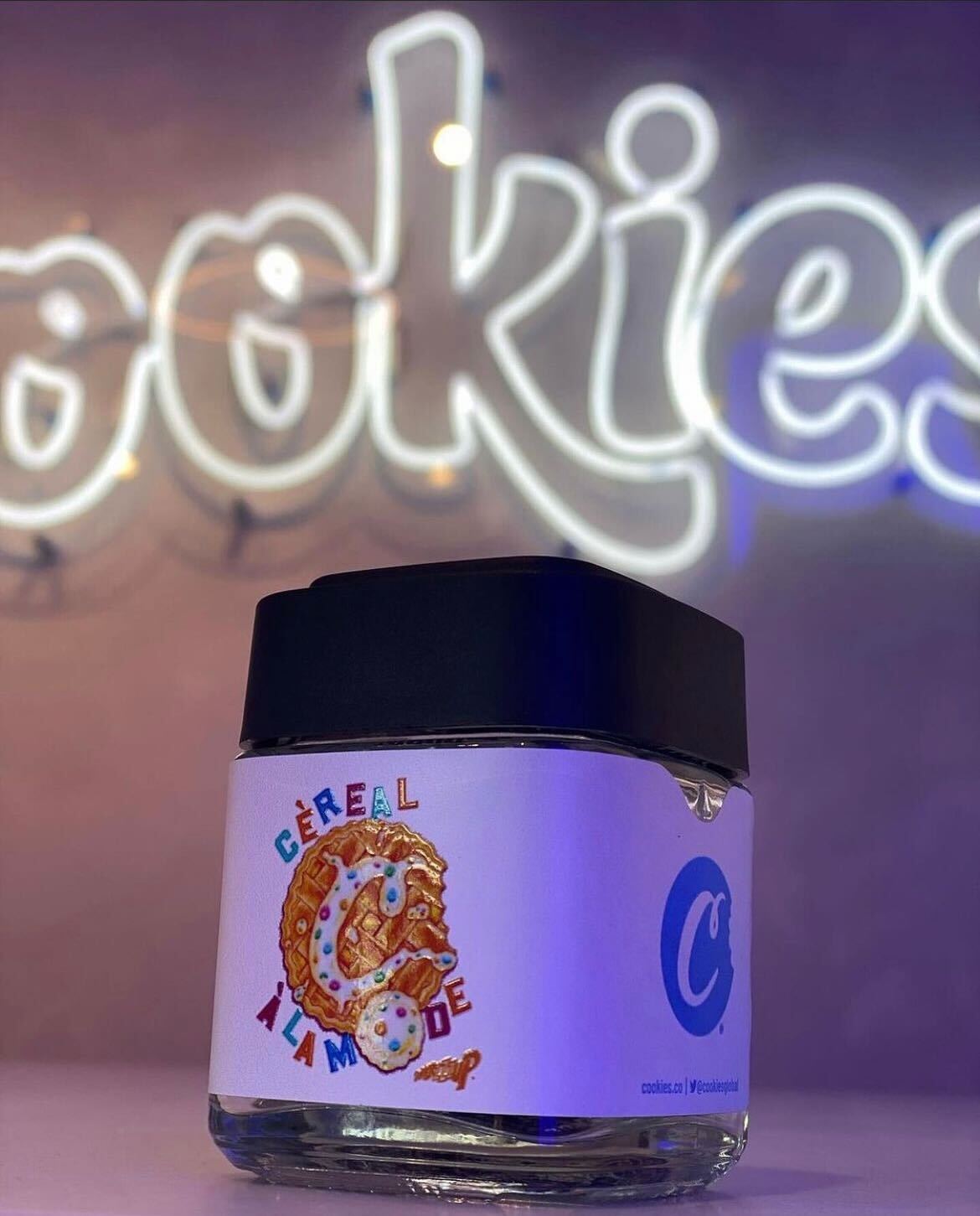 Calyx jar with custom Cookies branding in front of neon Cookies sign in the background